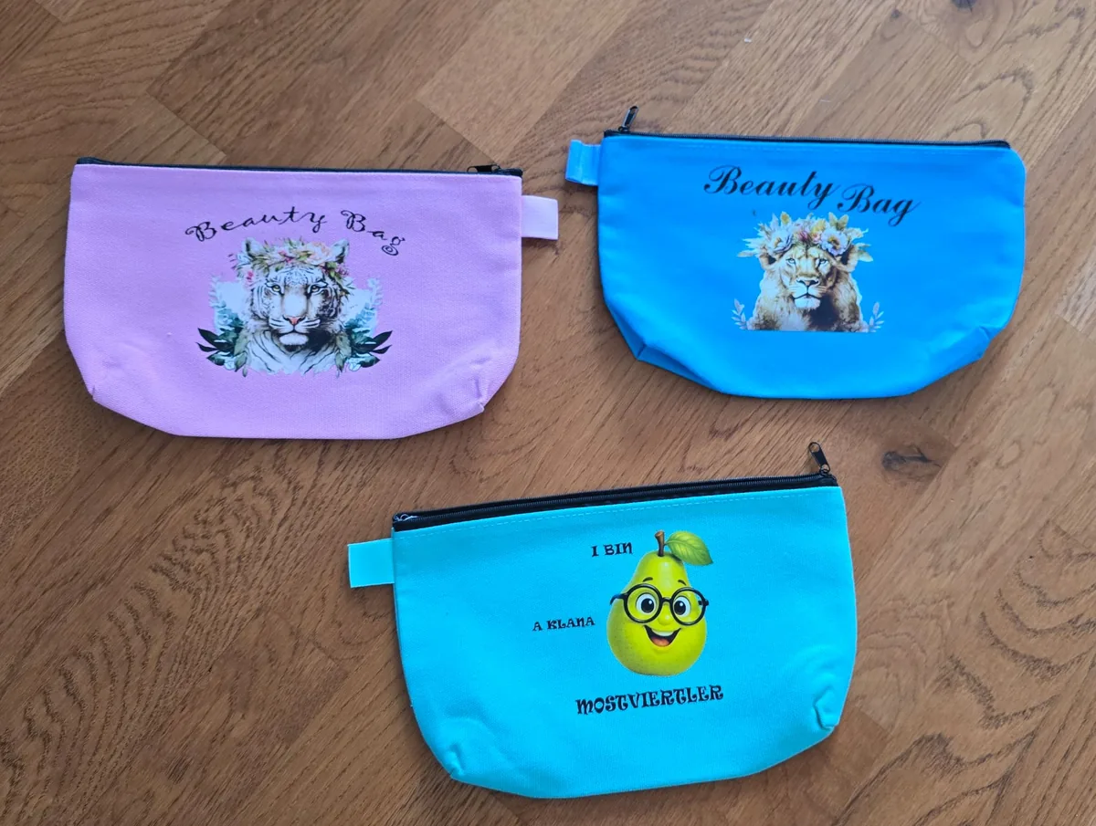 Drei bunte Reißverschlusstaschen mit Tiger-, Löwen- und Birnen-Motiven