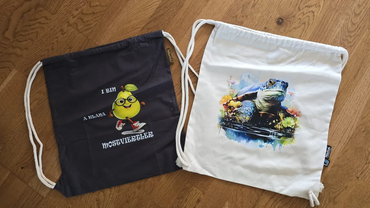 Schwarzer Turnbeutel mit Birnenmann und weißer Beutel mit farbenfrohem Schildkröten-Aquarelldruck