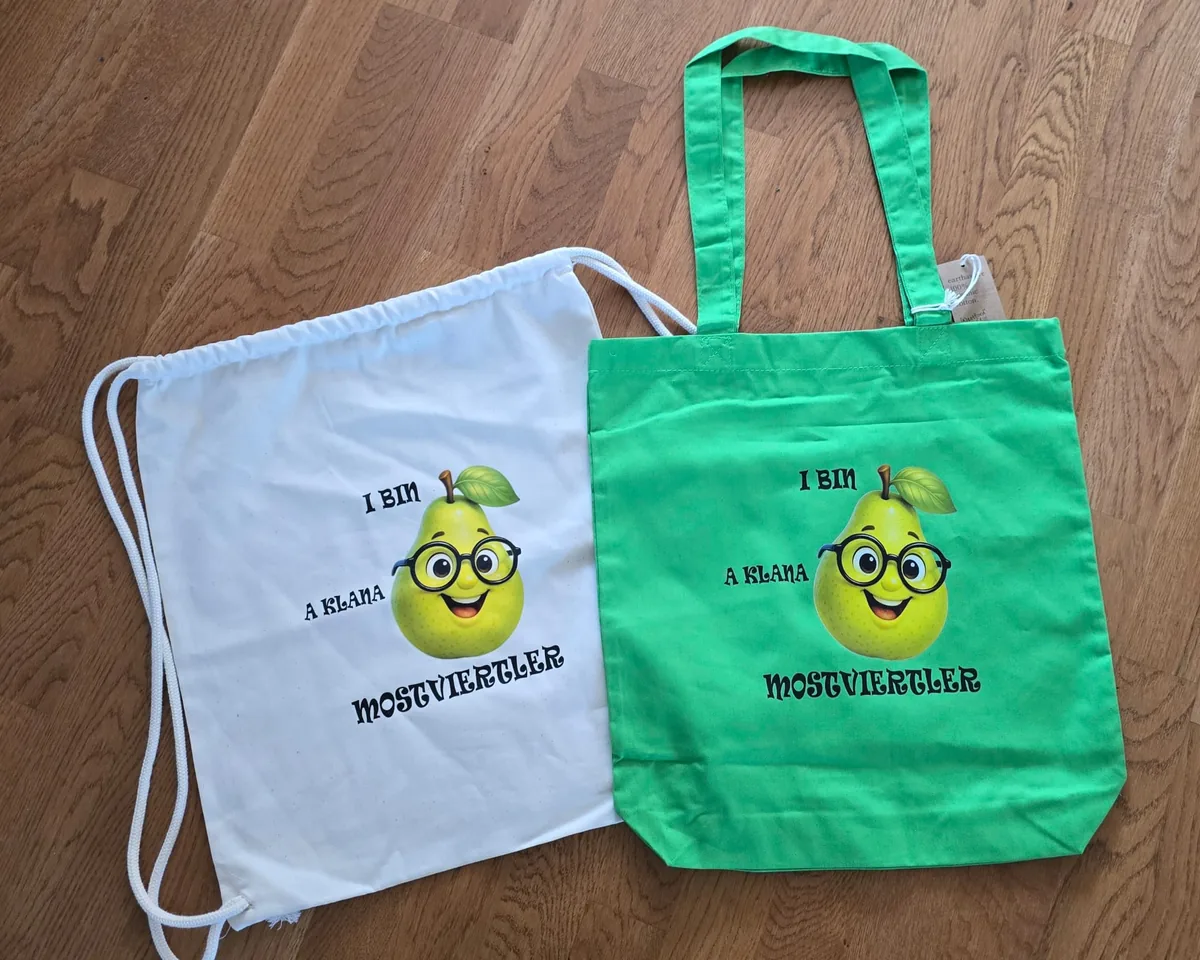 Weißer Turnbeutel und grüne Baumwolltasche mit I bin a klana Mostviertler Aufdruck