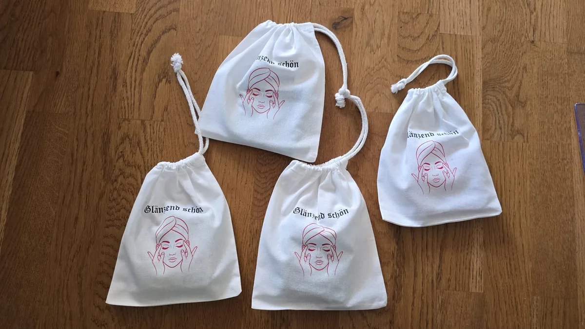 Vier weiße Baumwollsäckchen mit Kordelzug und elegantem Beauty-Motivdruck