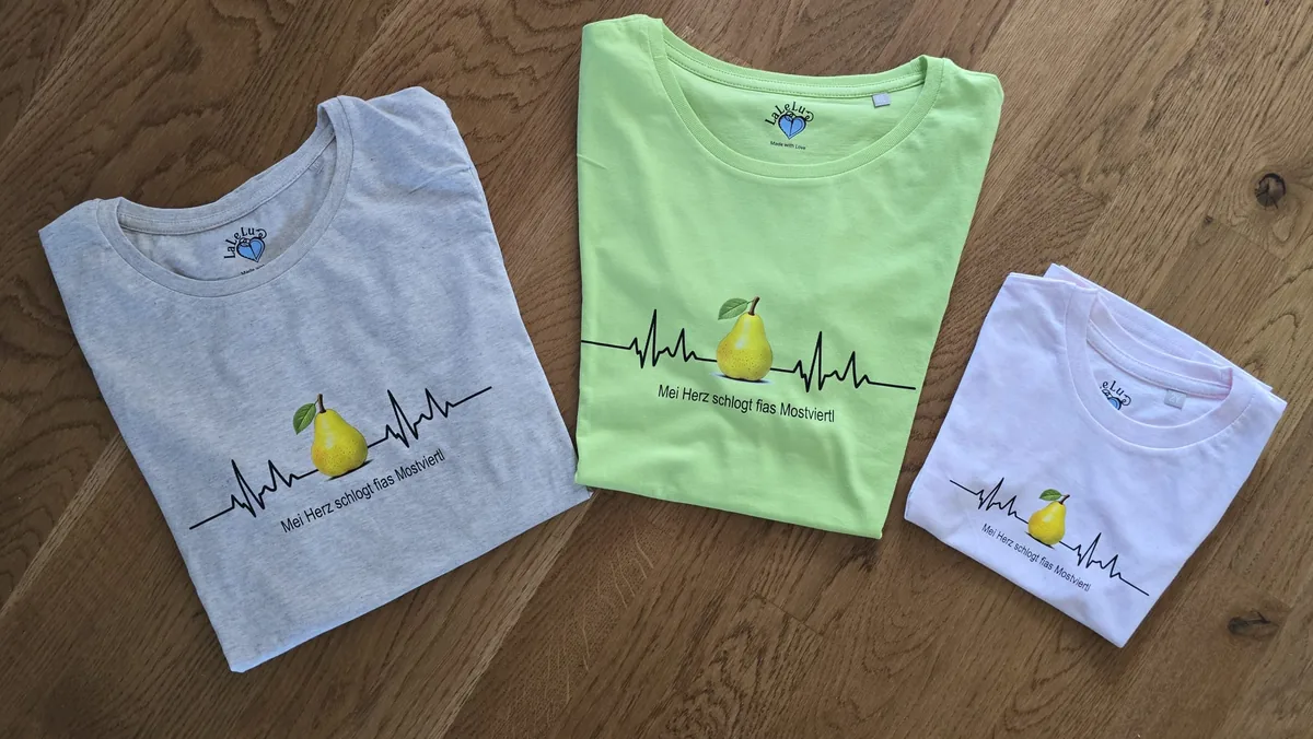 Drei gefaltete T-Shirts in Grau, Hellgrün und Rosa mit Birnen-EKG Herzschlagdruck