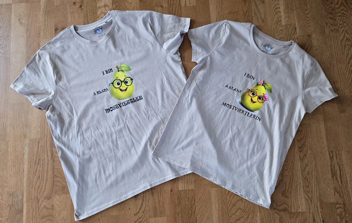 Zwei beige T-Shirts nebeneinander: I bin a klana Mostviertler und I bin a klane Mostviertlerin